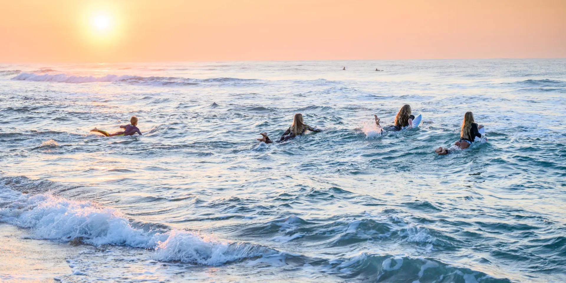 Surfers paddling out through the shorebreak at Salt Rock Beach at sunrise
