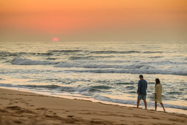 A couple walking the shoreline at sunrise