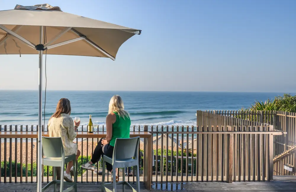 Residents seated under an umbrella looking out over the sea