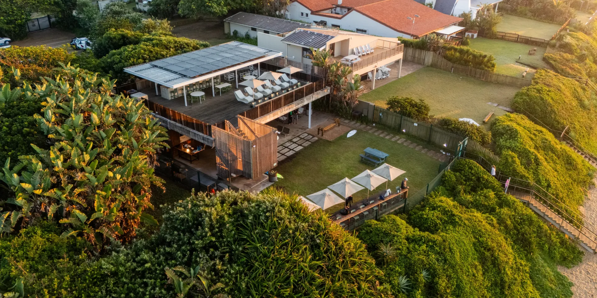 The beach clubhouse from above, its decks set among the trees above the beach