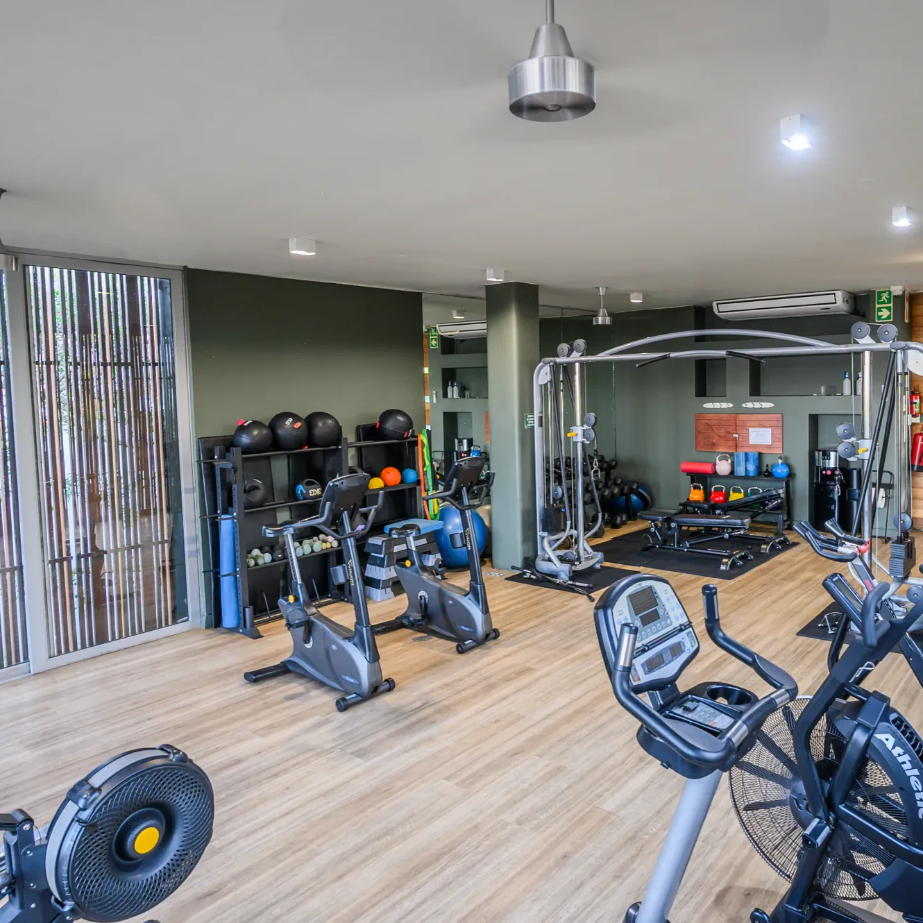 The estate gym, with exercise bikes and a rack of medicine balls beside a wall of glazing