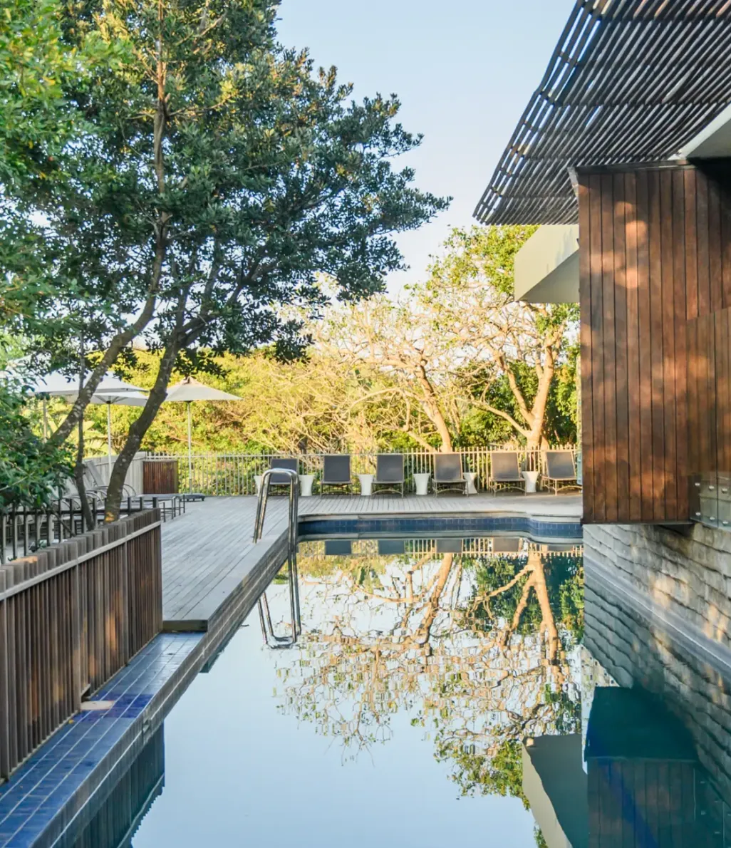 The outdoor pool alongside the clubhouse, trees reflected in the water